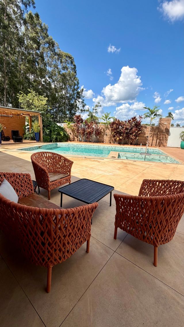 Poltronas e mesa de centro no deck, com a piscina ao fundo
