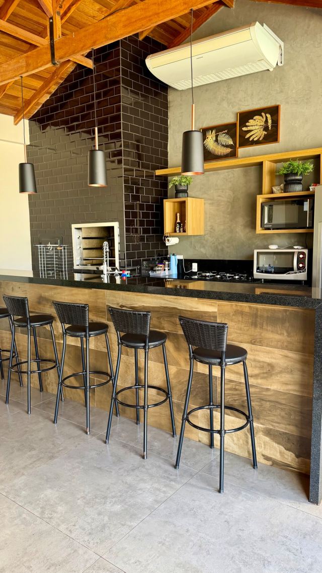 Área gourmet com bancada, banquetas e churrasqueira